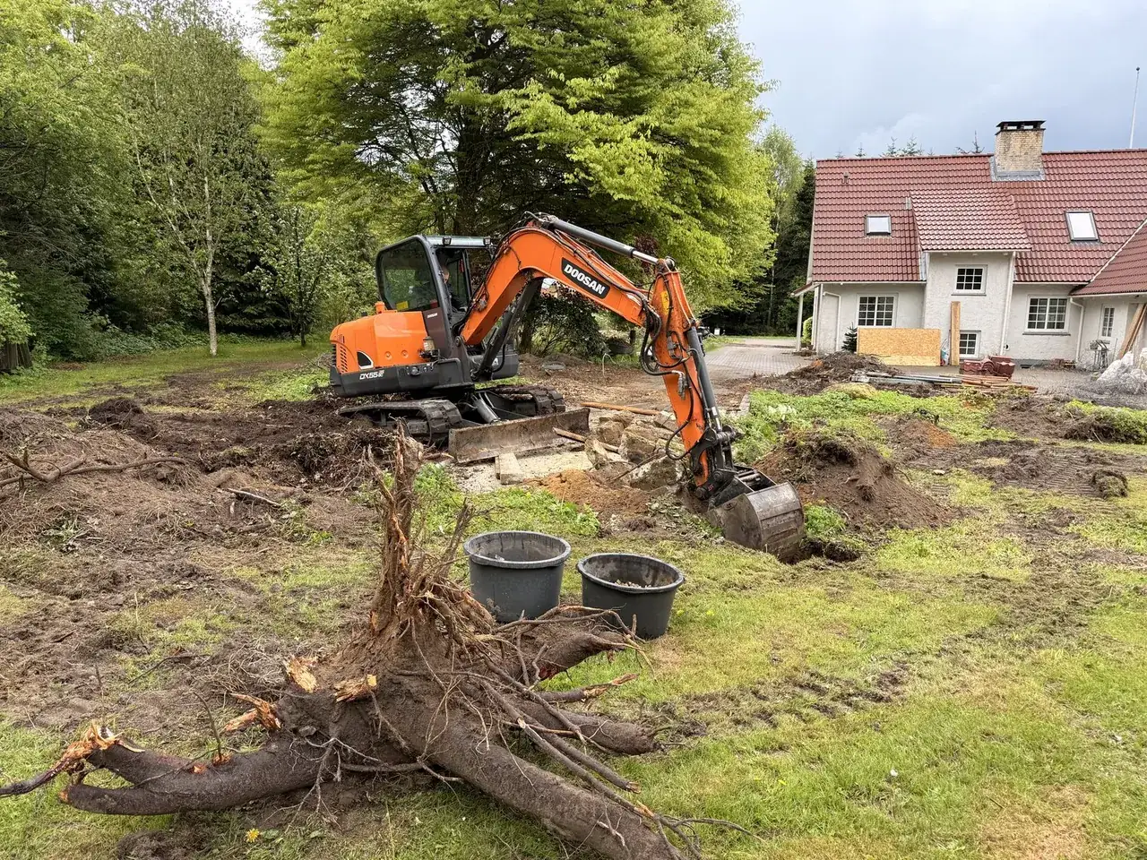 Minigraver og oprodet stub på en grund under rydning