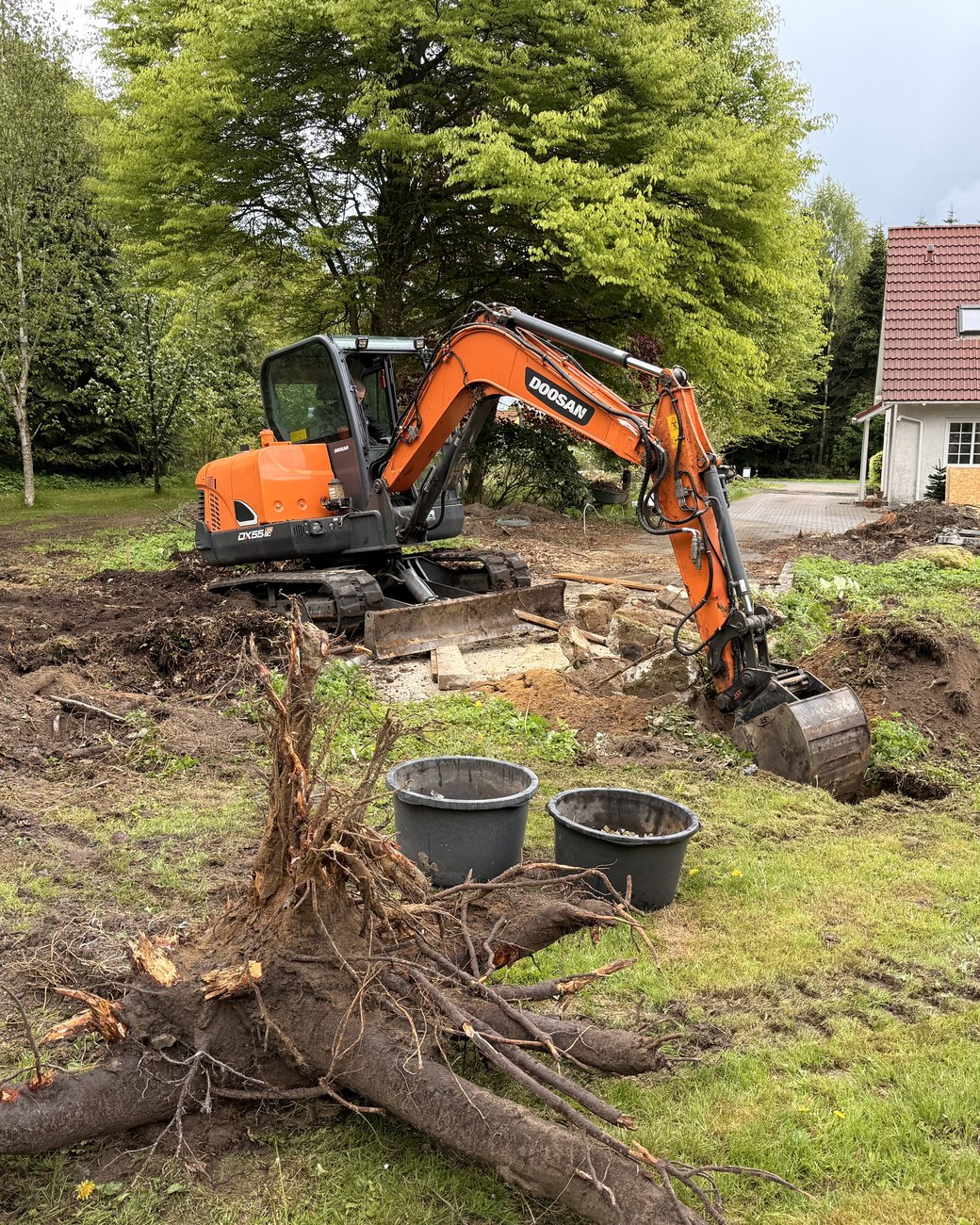 Minigraver i gang med at grave stub og rødder fri på en grund