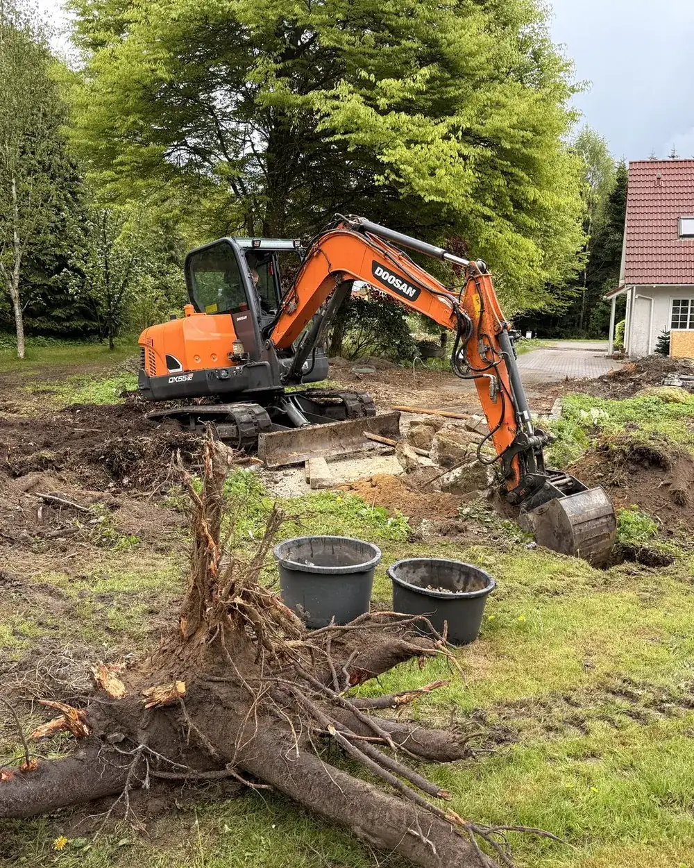Minigraver i gang med at grave stub og rødder fri på en grund